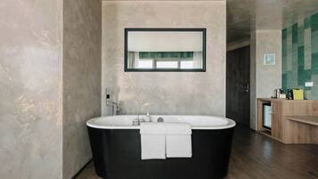 A modern bathroom with a freestanding bathtub, a mirror above it, and a wooden vanity with a sink.