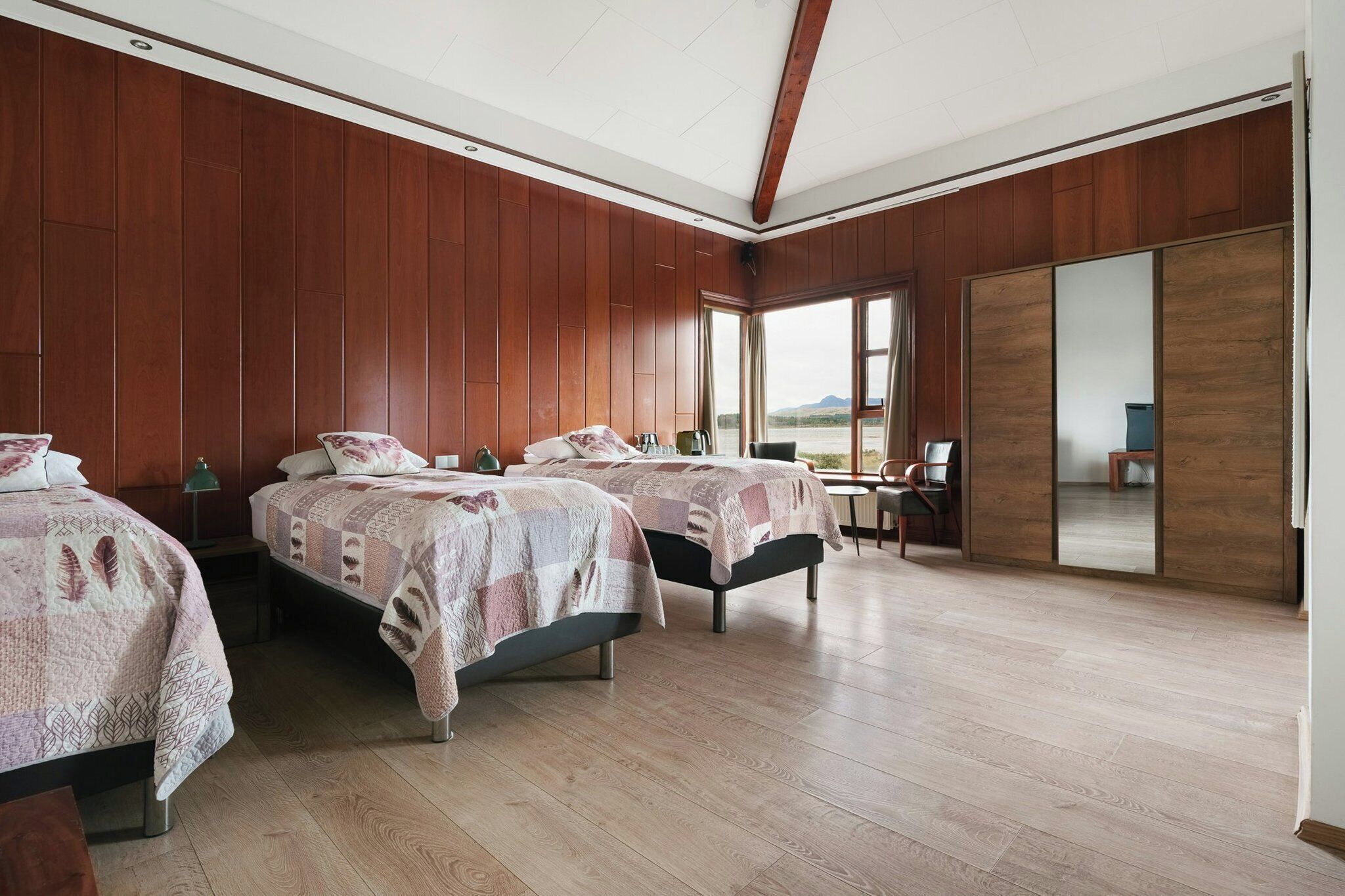 Habitación de hotel con dos camas, un escritorio y vistas al exterior.
