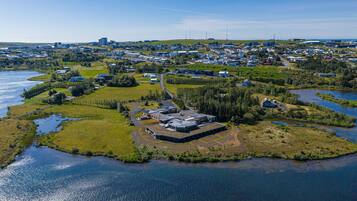 An aerial view of a coastal area with a large building complex surrounded by water and greenery.