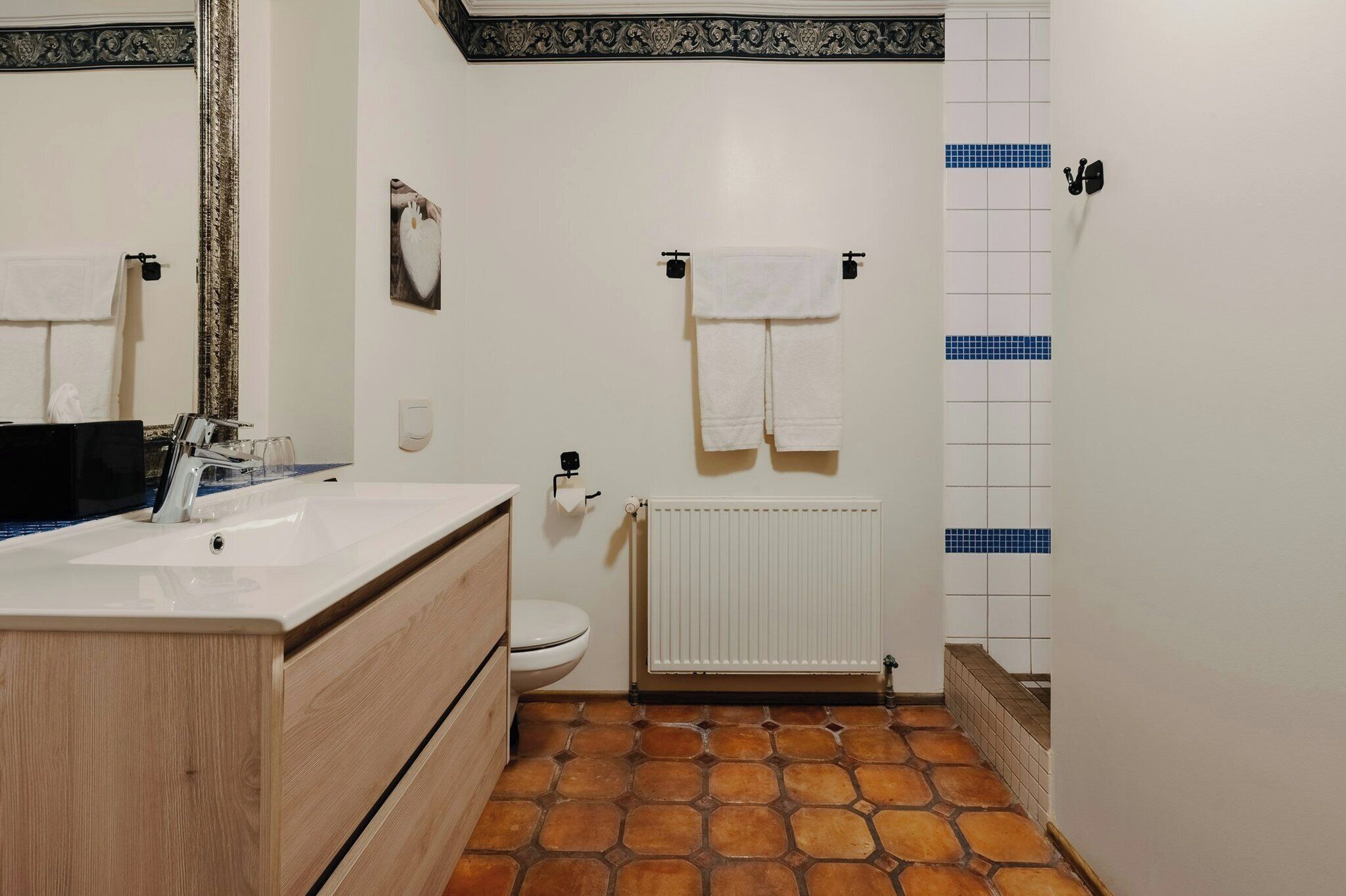 Un baño con un lavamanos blanco, un inodoro, un perchero para toallas y un radiador.