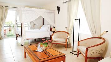 A hotel room with a bed, two chairs, a coffee table, and a large window with curtains.
