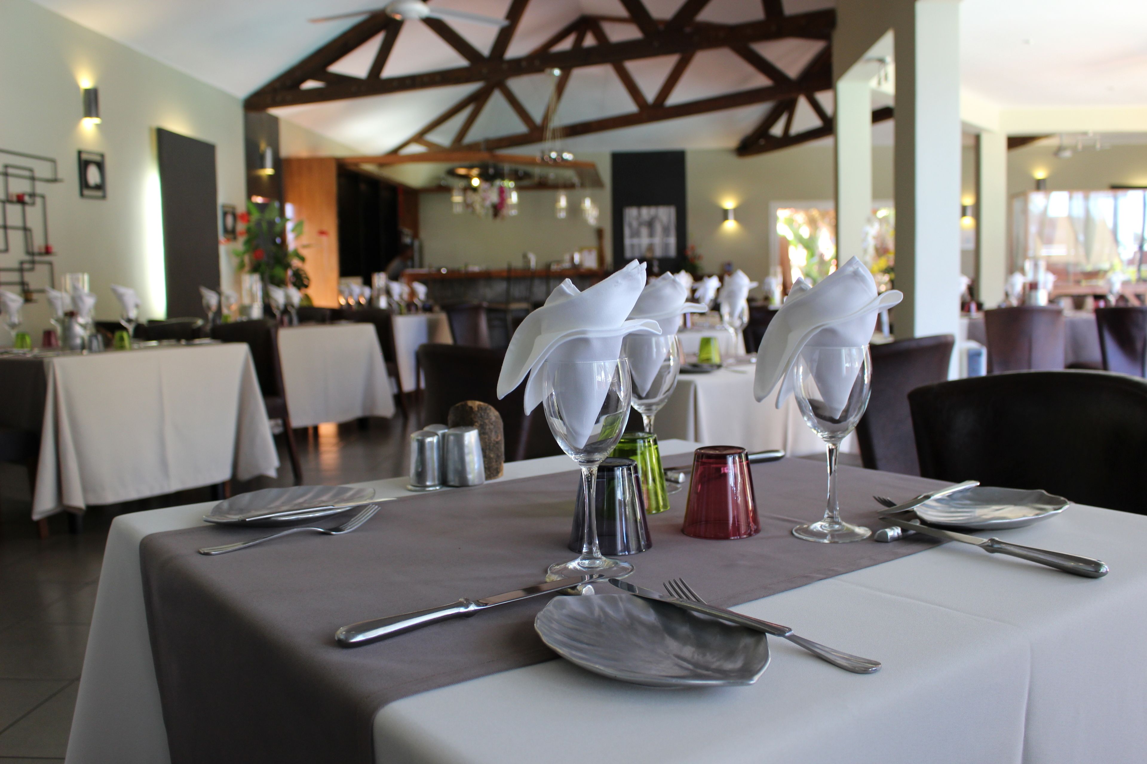 A dining area with tables set for a meal, featuring neatly arranged cutlery and wine glasses.