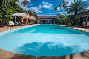 Una piscina al aire libre, sombrillas, sillones reclinables de piscina
