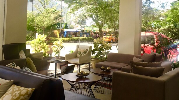 Un amplio espacio interior con zona de estar, un diseño de techo moderno, ventanas grandes que ofrecen vistas al exterior y diversas opciones de asientos, incluyendo sofás y sillones.