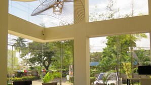 Un salón amplio con un sofá grande, una mesa de centro y un mueble para televisión. Ventanas grandes ofrecen vistas al exterior.