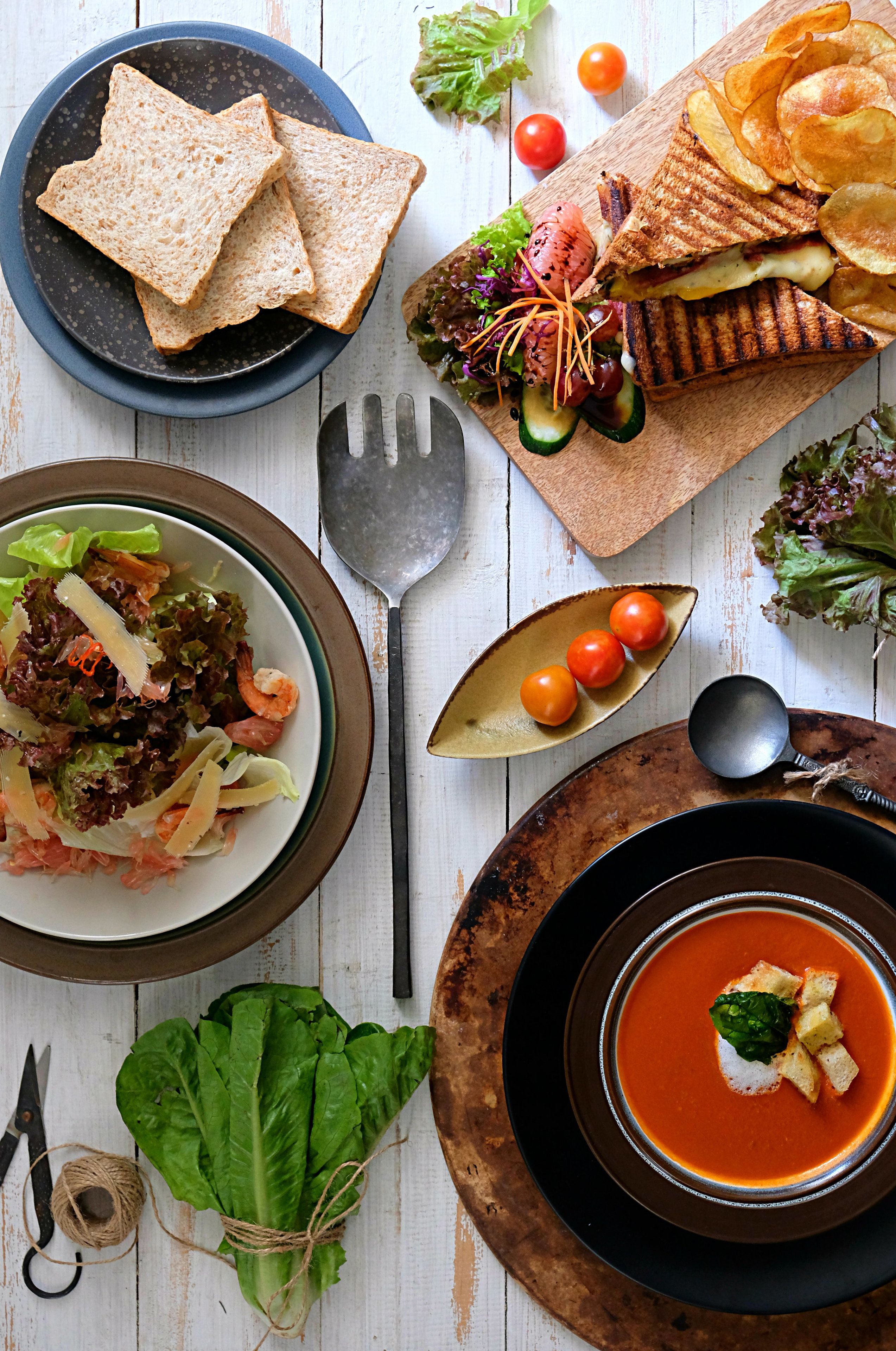 A table with various food items including sandwiches, salad, and soup.
