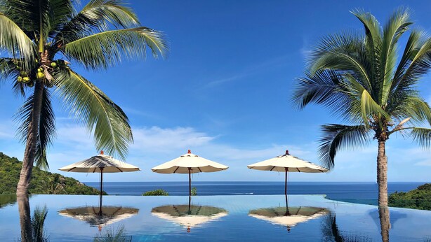 An infinity pool with three umbrellas and palm trees, overlooking a clear blue sea. - Tanote Villa (Koh Tao)