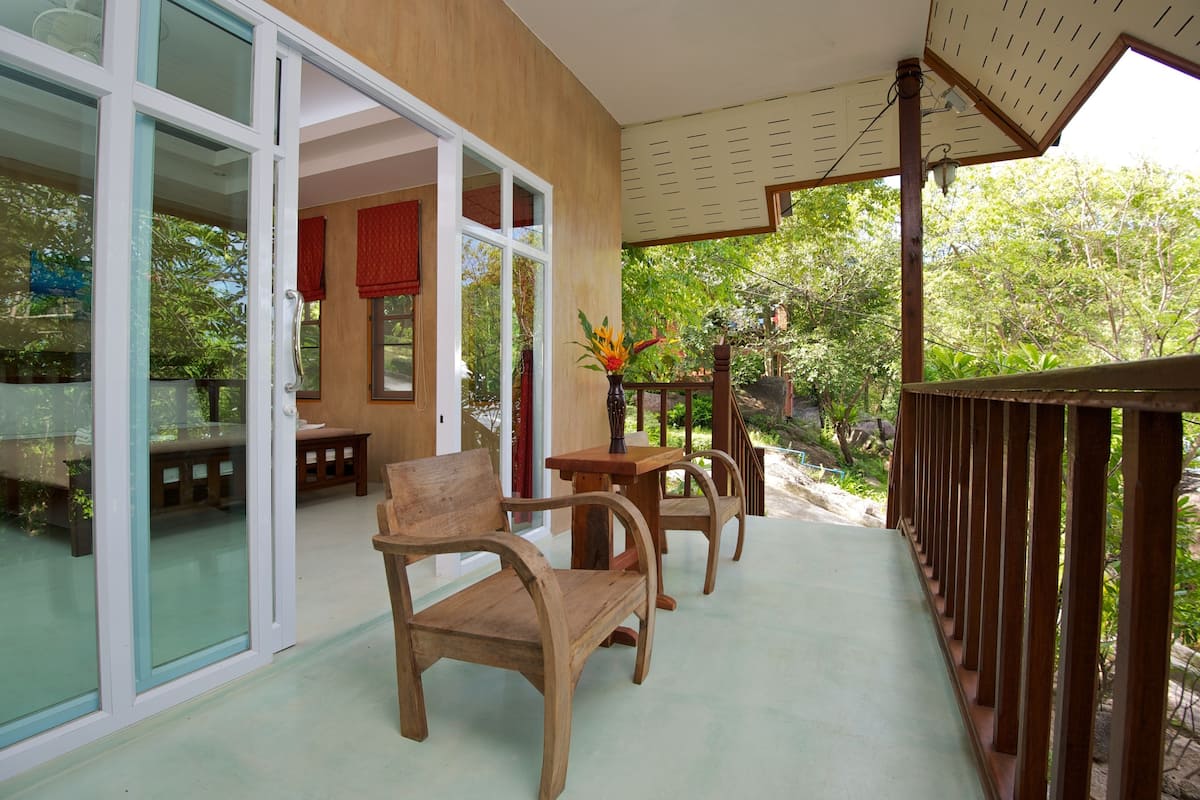 An outdoor seating area with wooden furniture and a glass door leading to a room.