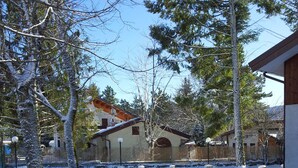 A snow-covered courtyard with a building featuring a sloped roof and a wooden fence. - Rifugio del Pettirosso (Pescasseroli)