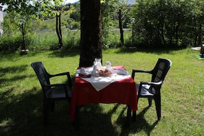 A picnic table set outdoors with a red tablecloth, two chairs, and a meal setup including plates, a pitcher, and a glass. - Rifugio del Pettirosso (Pescasseroli)