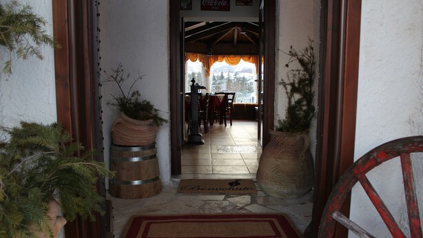 A wooden door leading to a room with a tiled floor, a bench, and a large potted plant. - Rifugio del Pettirosso (Pescasseroli)
