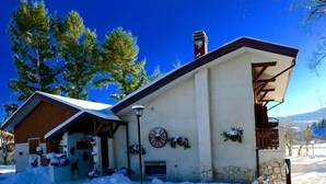 A two-story building with a stone facade, a wooden porch, and a snow-covered roof. - Rifugio del Pettirosso (Pescasseroli)