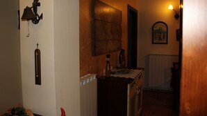 A hallway with a wooden cabinet, a wall-mounted clock, and a framed picture. - Rifugio del Pettirosso (Pescasseroli)