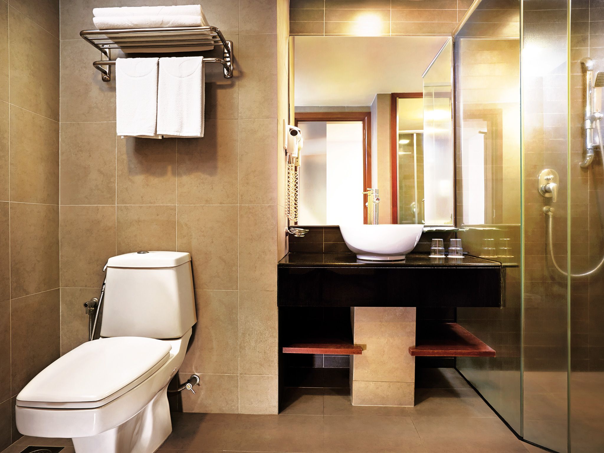 Un baño moderno con inodoro, lavamanos, espejo y ducha.