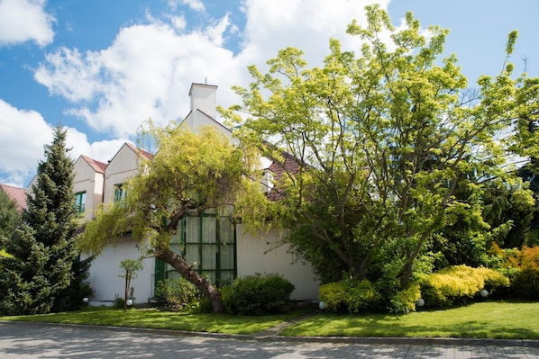 A two-story house with a large tree in the front yard.