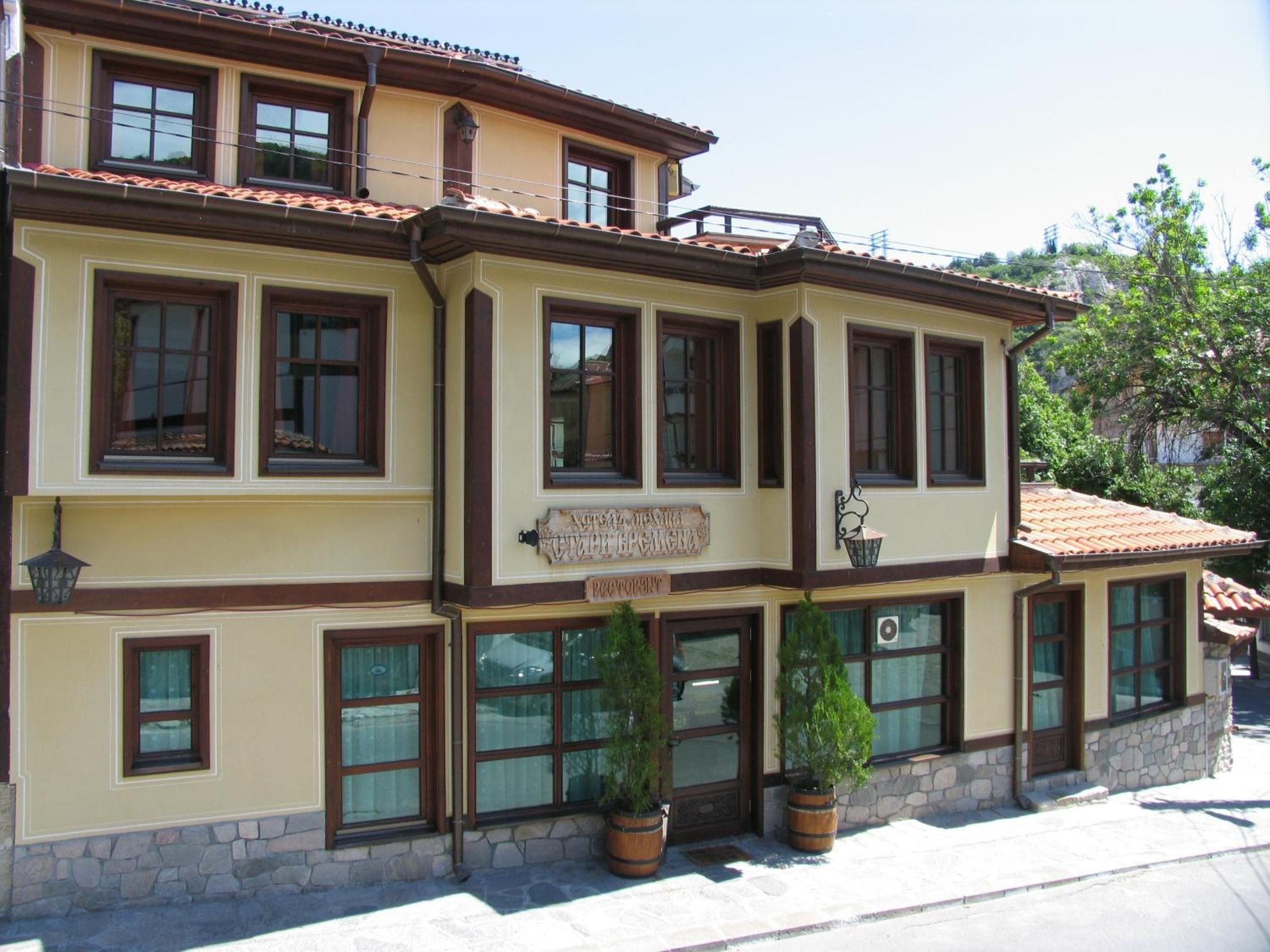 Un edificio de dos pisos con múltiples ventanas, un letrero que dice 'Hotel' y escalones de piedra que conducen a la entrada.