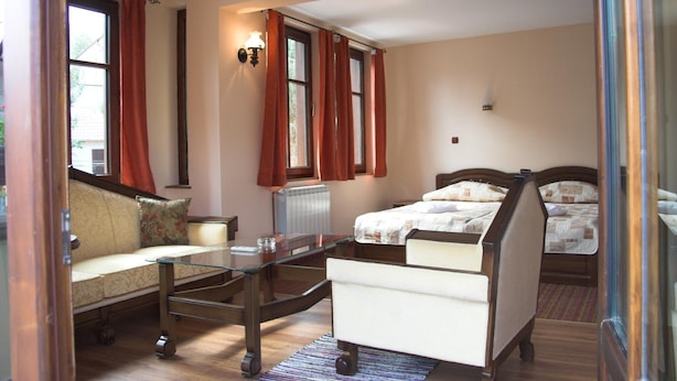 A room with a sofa, a glass-top table, a bed, and a radiator.