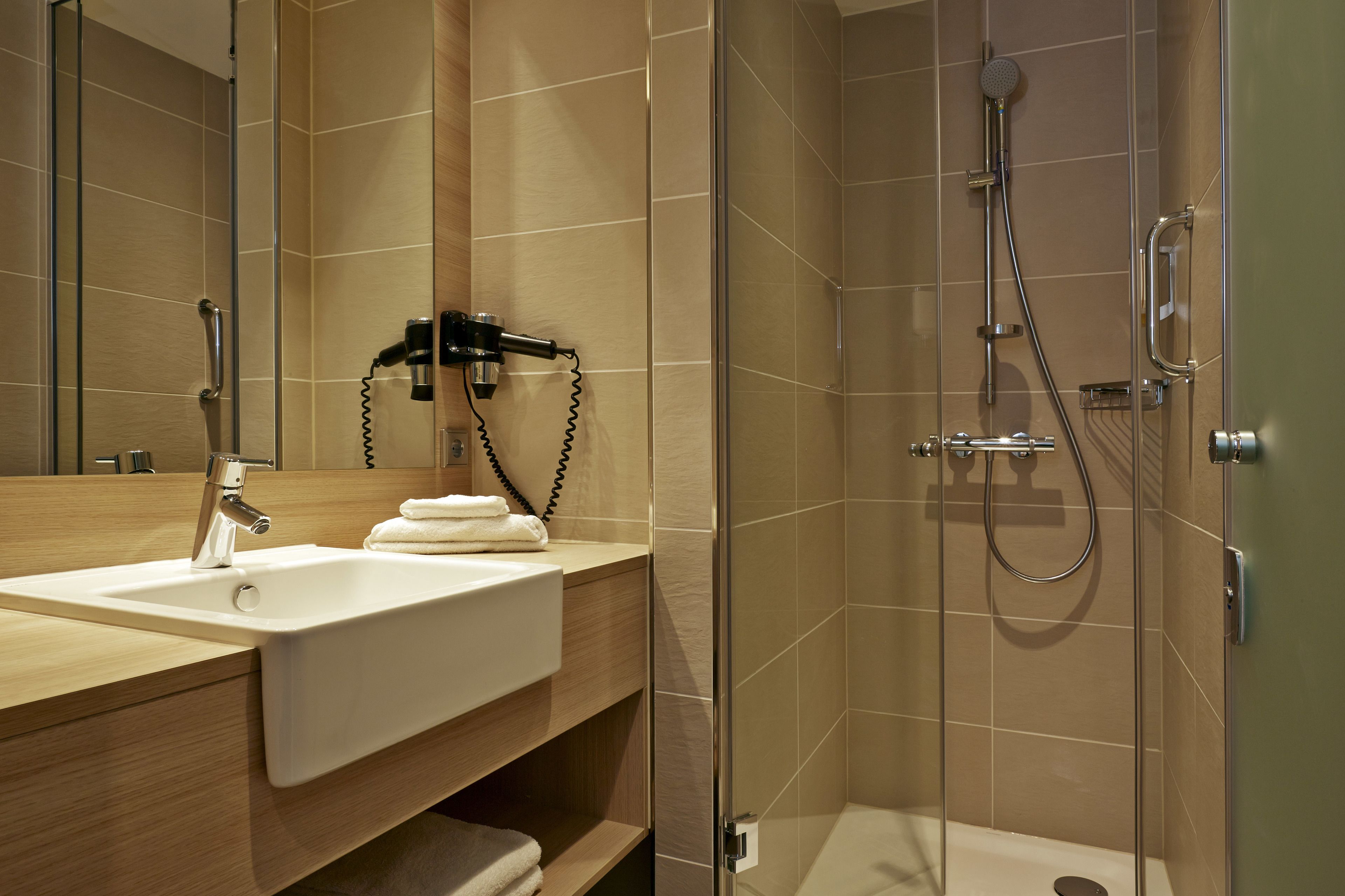 A modern bathroom with a glass-enclosed shower, a sink with a towel, and a mirror.