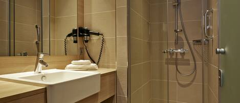 A modern bathroom with a glass-enclosed shower, a sink with a towel, and a mirror.
