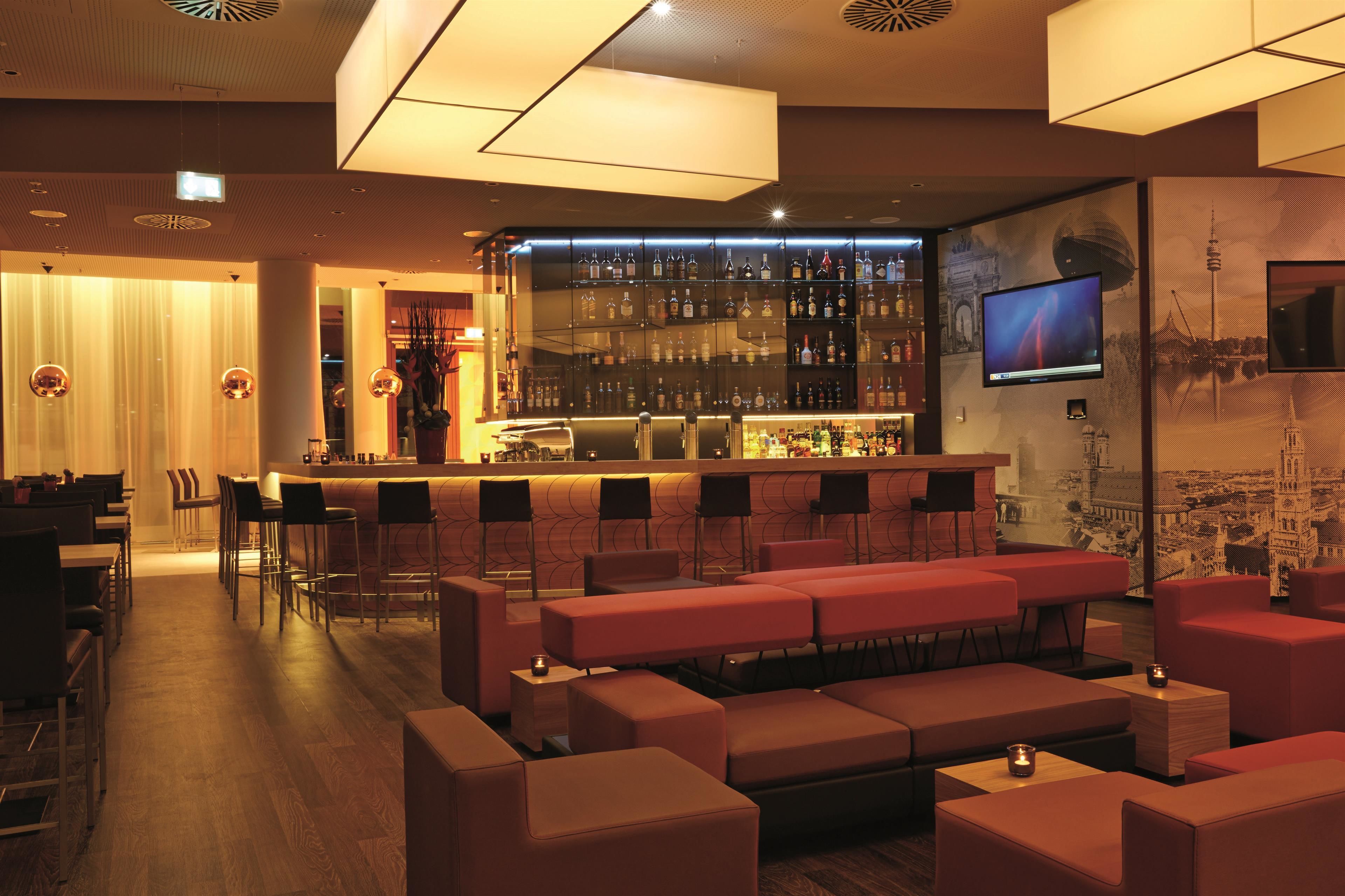 A bar area with a long counter, multiple seating options, and a television screen.