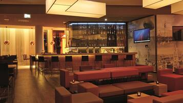 A bar area with a long counter, multiple seating options, and a television screen.