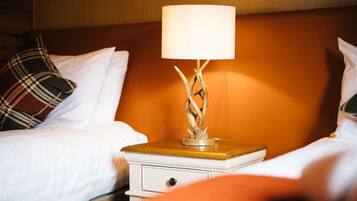 Een hotelkamer met een bed, een nachtkastje met een lamp en een houten hoofdeinde.