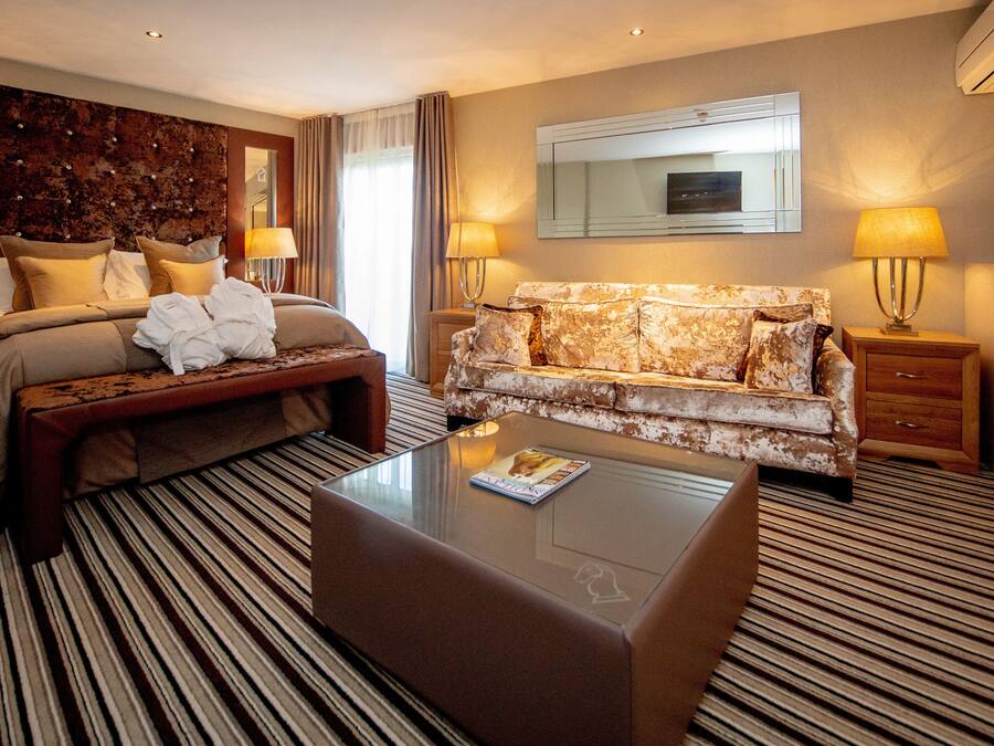 Een hotelkamer met een bed, een bank, een bijzettafeltje en een spiegel.