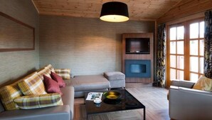 A modern living room with a wooden ceiling, a sofa set, a coffee table, and a television. - Ingliston Country Club Hotel (Bishopton)