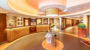 A hotel lobby with a reception desk, a round table with a vase, and a decorative ceiling. - Ingliston Country Club Hotel (Bishopton)