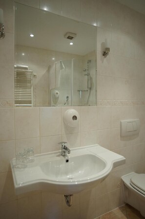 A bathroom with a sink, mirror, shower, and toilet. - Hotel Grodzki (Poznań)