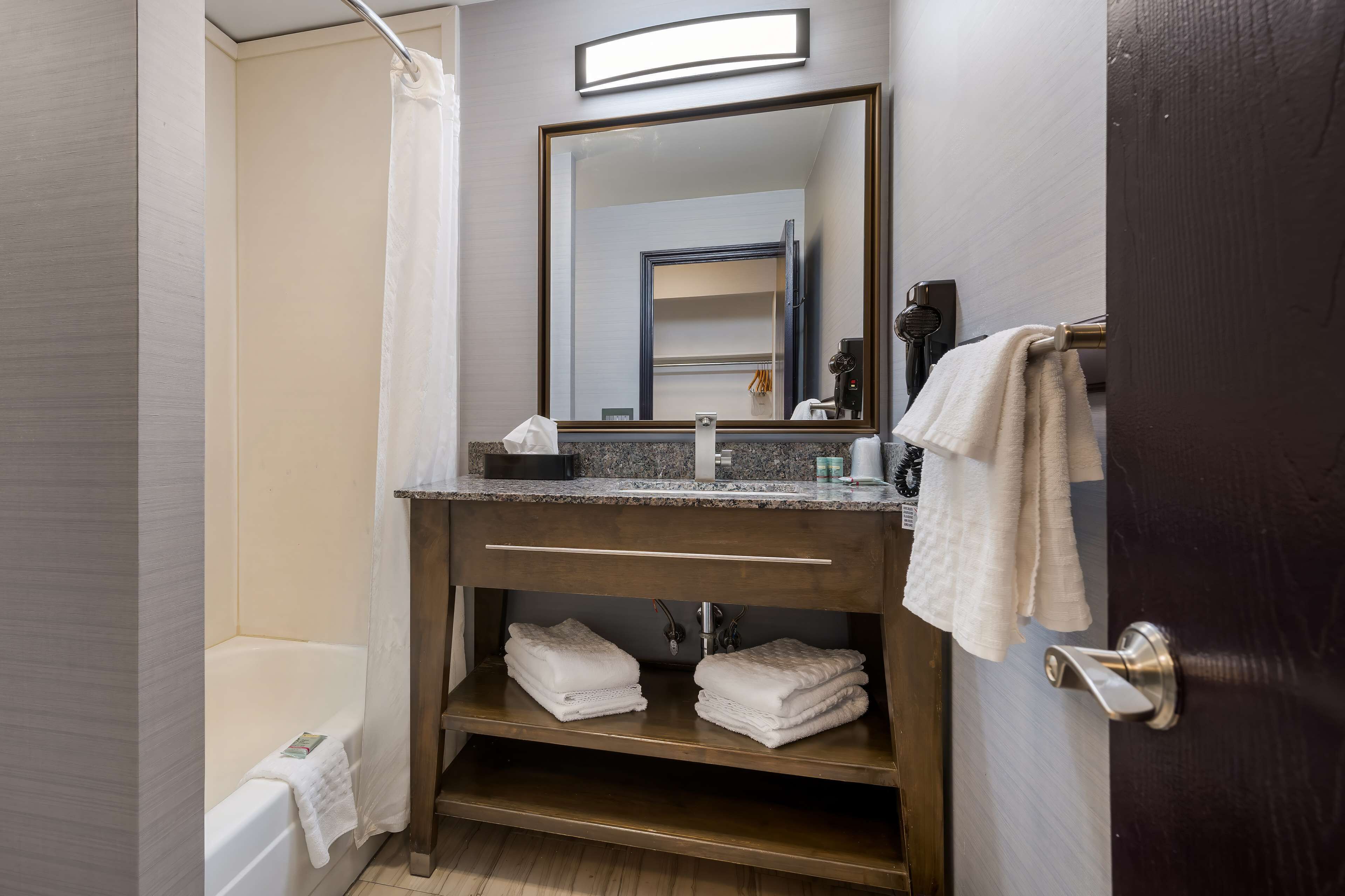 A bathroom with a bathtub, a vanity with a mirror, and a towel rack.