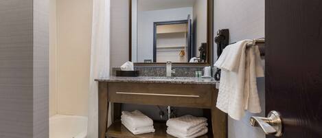 A bathroom with a bathtub, a vanity with a mirror, and a towel rack.