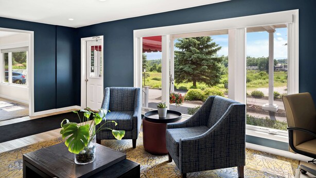 A modern living room with dark blue walls, large windows, and a view of a landscaped garden. - Best Western Freeport Inn (Freeport)