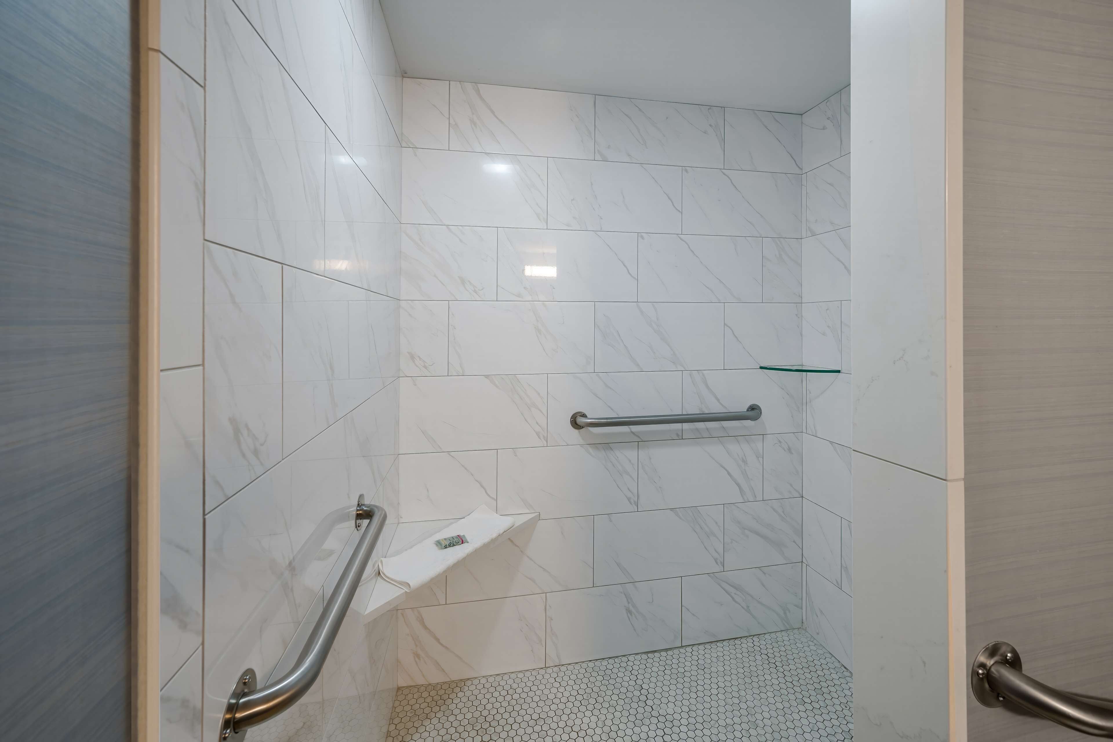 Een badkamer met witte marmeren tegels, een handgreep en een klein plankje.