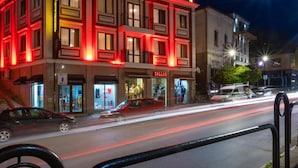A multi-story building with illuminated signage, a storefront, and a street view with vehicles. - Real Hotel Veliko Tarnovo (Veliko Tarnovo)