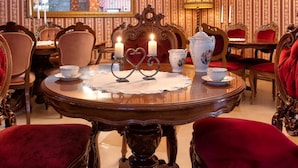 A formal dining room with a chandelier, ornate chairs, and a table set for tea. - Real Hotel Veliko Tarnovo (Veliko Tarnovo)