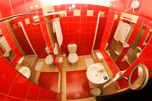 A bathroom with red tiles, a white toilet, a sink, and a mirror.