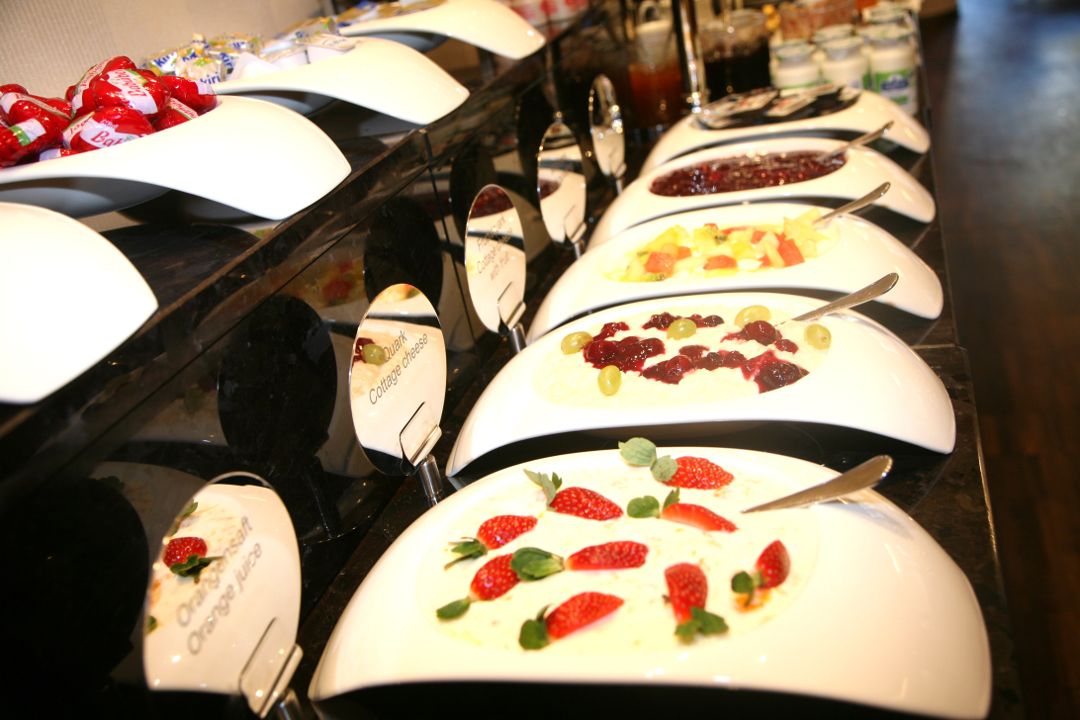 Un buffet con diversi piatti, tra cui una sezione dedicata al formaggio fresco e un'altra alle fragole.