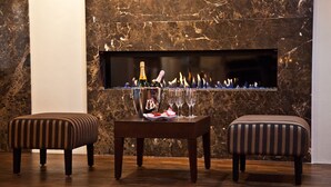 A modern interior with a marble wall, a fireplace, and two striped ottomans. -  Favor Hotel Königsallee (Düsseldorf)