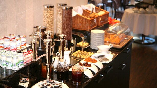 A buffet with various food items and beverages, including yogurt, cereal, and a coffee station. -  Favor Hotel Königsallee (Düsseldorf)