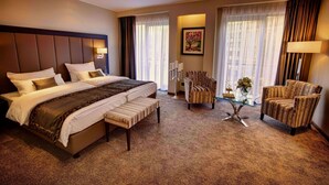 A hotel room with a large bed, a bench, a chair, a small table, and a painting on the wall. -  Favor Hotel Königsallee (Düsseldorf)