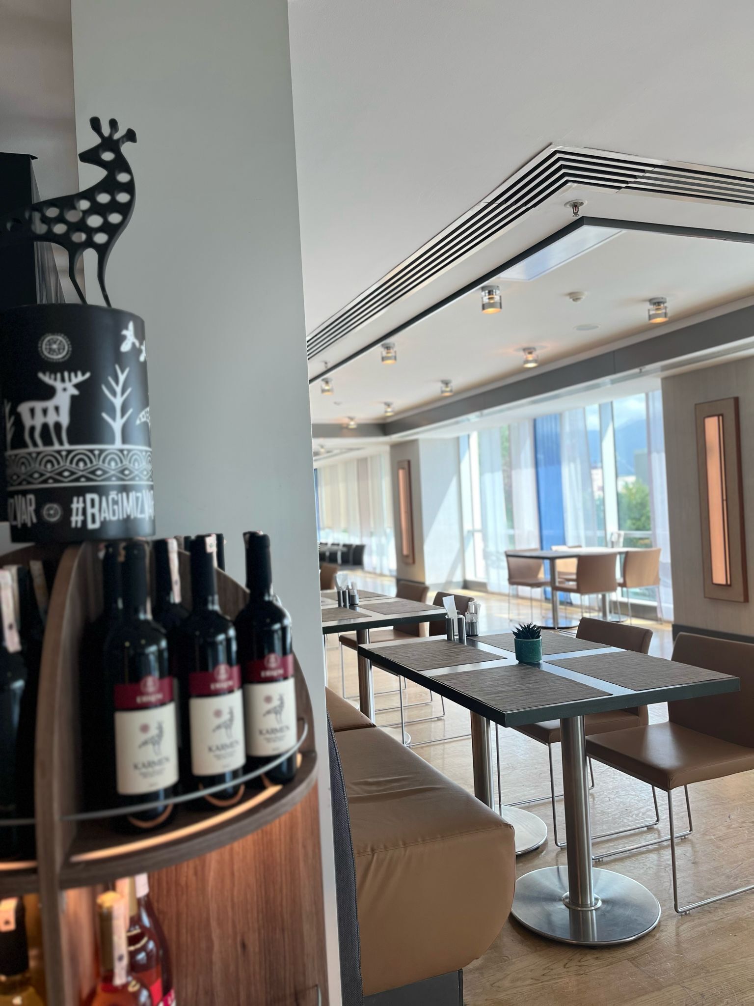 A modern dining area with a bar, seating, and large windows.
