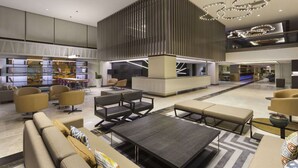 A spacious lobby with a central seating area, a reception desk, and a modern staircase.