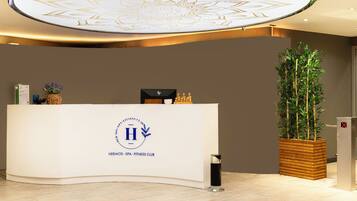 A reception desk with a logo, a potted plant, and a modern ceiling design.