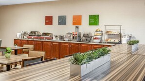A modern breakfast area with a long counter, various food stations, and seating arrangements. - Comfort Inn Lexington South (Nicholasville)