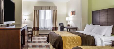 A hotel room with two beds, a desk with a TV, a chair, a lamp, and a view of the outdoors through a window.
