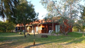 A building with a covered patio area, outdoor seating, and a grassy lawn.