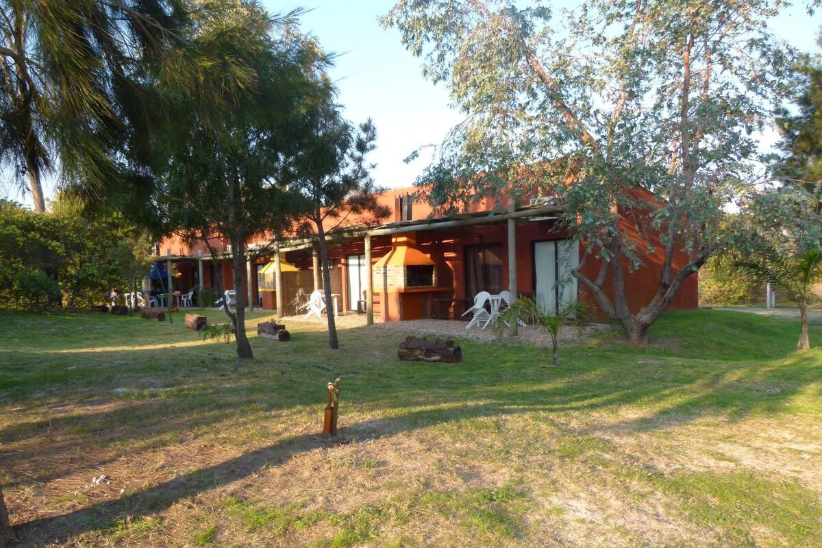 A building with a covered patio area, outdoor seating, and a grassy lawn.