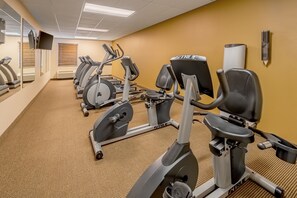 A gym with stationary bikes, treadmills, and a mirrored wall. - Landmark Suites (Williston)