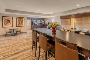 A spacious kitchen with modern appliances, a dining area with a long table and chairs, and artwork on the walls. - Landmark Suites (Williston)